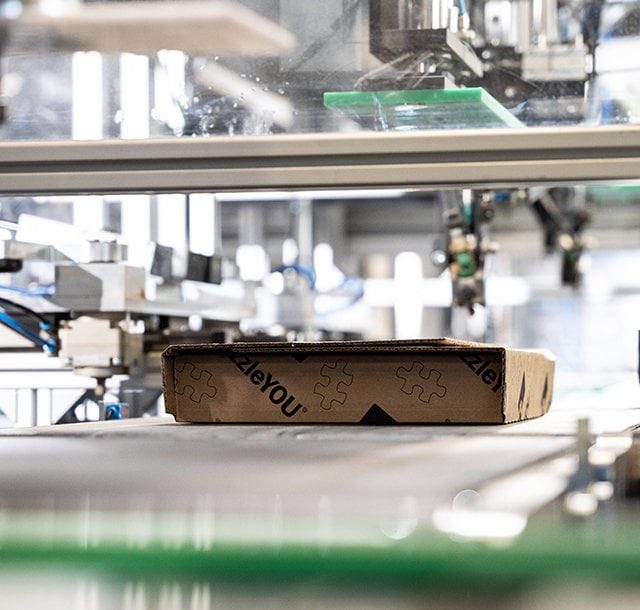 Via Förderbänder fahren die fertig produzierten Fotopuzzles direkt in die Verpackungsstation